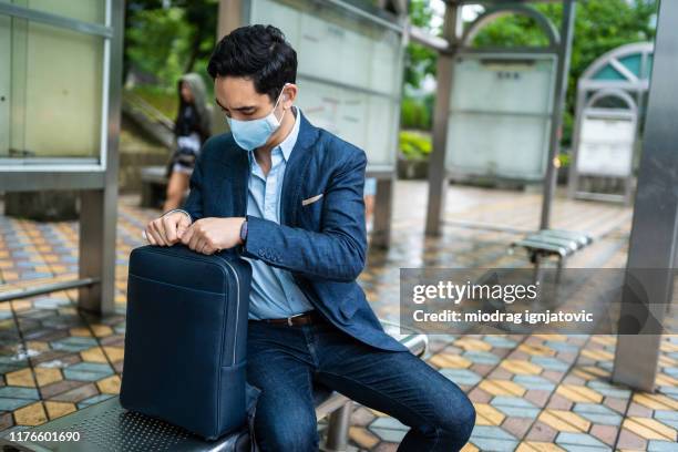 businessman with mask for air pollution sitting on bus station - laptop bag mask stock pictures, royalty-free photos & images