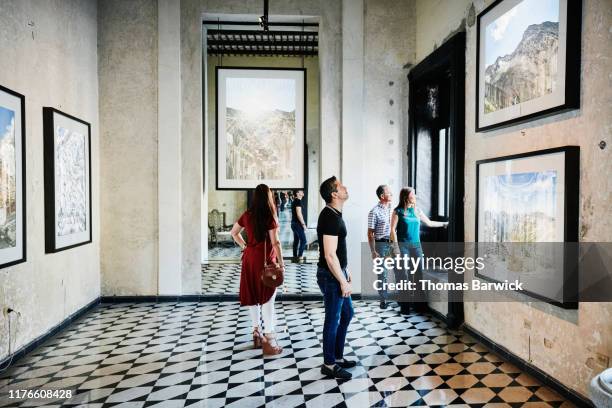 two couples admiring artwork while touring museum during vacation - displays photos et images de collection