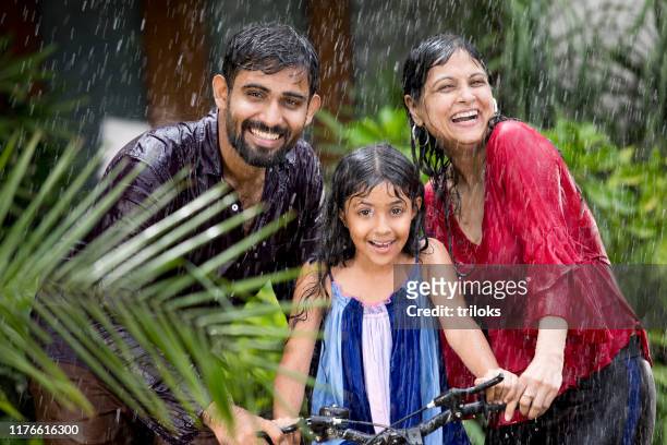 famiglia che si gode la pioggia - monsoni foto e immagini stock