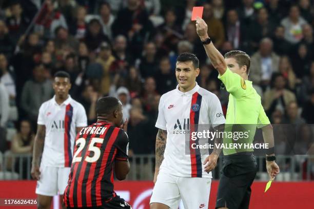 French referee François Letexier shows a red card to Nice's French midfielder Wylan Cyprien next to Paris Saint-Germain's Argentine midfielder...