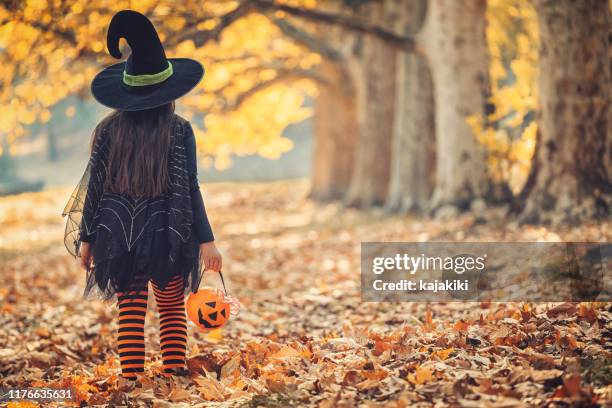 little girl in witch costume having fun on halloween trick or treat - witch hat stock pictures, royalty-free photos & images