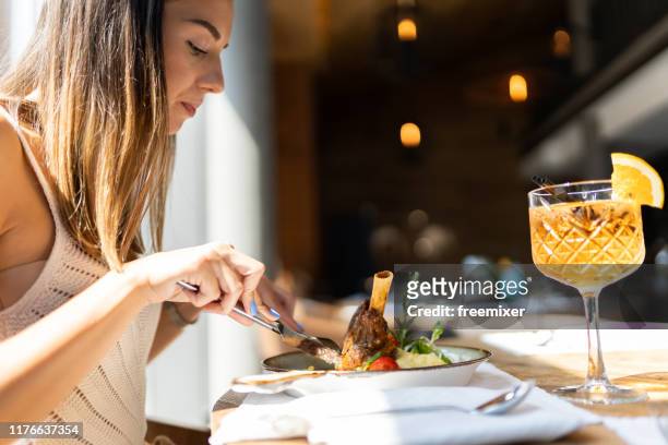 beautiful woman eating braised lamb in restaurant - leg of lamb stock pictures, royalty-free photos & images