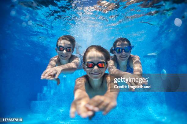 drei glückliche kinder schwimmen unter wasser im pool - öffentliches schwimmbad stock-fotos und bilder