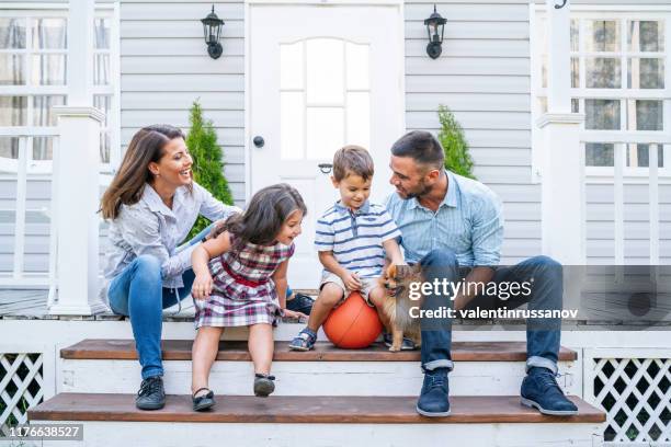 happy family with two kids sitting in front of american  porch - family porch stock pictures, royalty-free photos & images