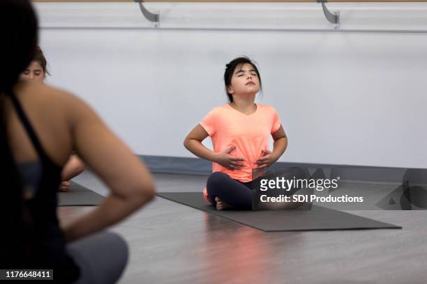 Young girl practices breathing exercises in yoga class