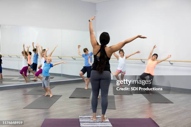 yoga instructor leads class for children - yoga teacher stock pictures, royalty-free photos & images