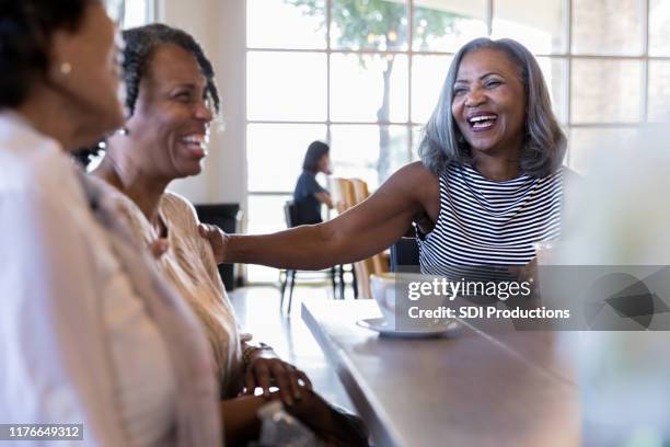 mature adult female friends laugh when they meet at cafe - coffee meeting with friends imagens e fotografias de stock