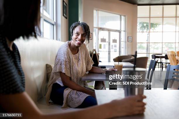 les femmes assises à des tables séparées parlent les unes avec les autres - individu étrange photos et images de collection