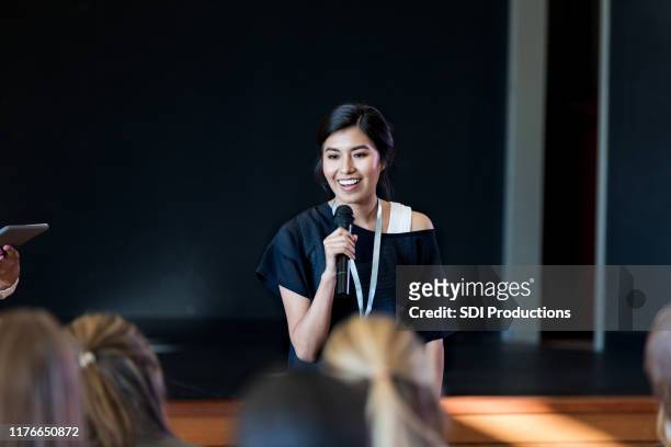 giovane influencer femminile parla con folla durante il seminario - festa per il lancio pubblicitario foto e immagini stock