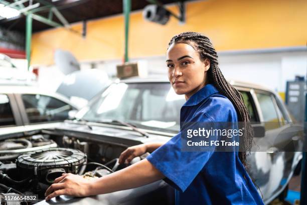 portrait of woman repairing a car in auto repair shop - stereotypical stock pictures, royalty-free photos & images