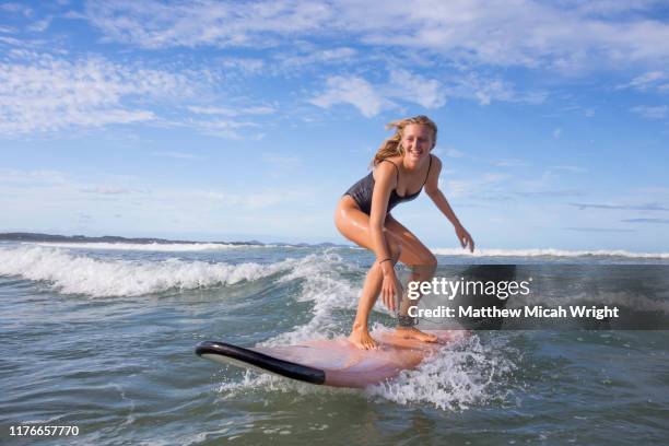 a young surfer girl out in the surf. - surfer by the beach australia stock-fotos und bilder