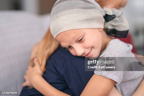 elementary age girl with cancer comforted by female doctor - bald girl stock pictures, royalty-free photos & images