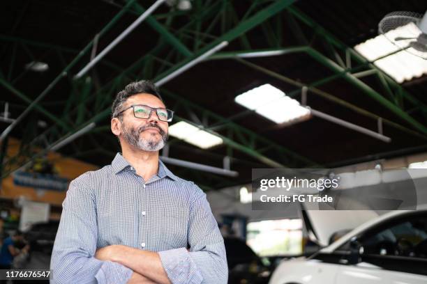 uomo in piedi con le braccia incrociate in un'officina di riparazione, disto allontanato - morena foto e immagini stock