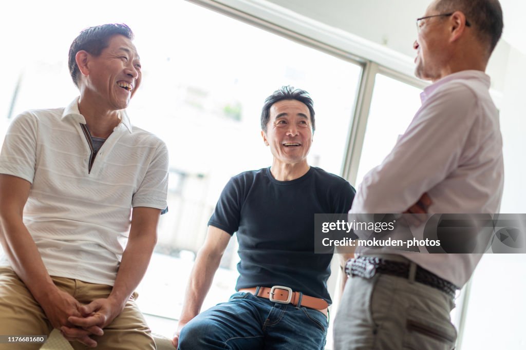 Three senior men talk happily
