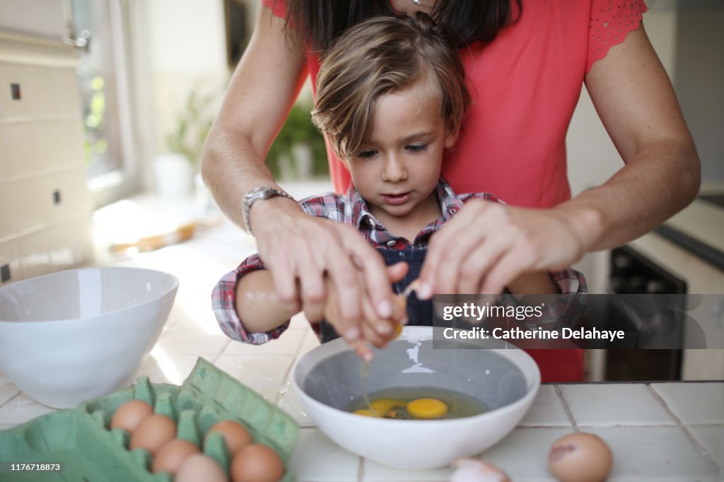 A 4 years old boy cooking at home with his mum