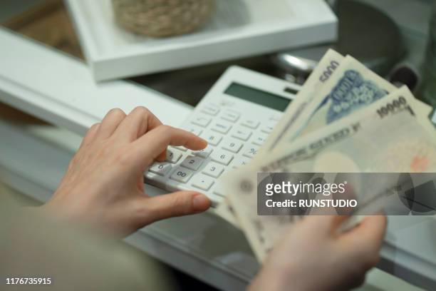 woman holding money with calculator - japanese currency stock pictures, royalty-free photos & images