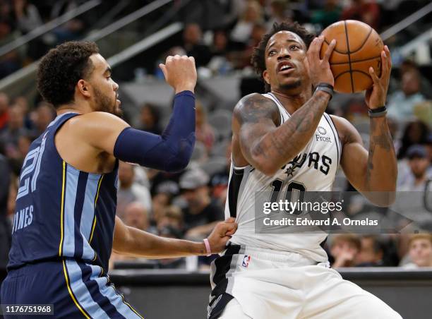 Tyus Jones of the Memphis Grizzlies defends DeMar DeRozan of the San Antonio Spurs during a preseason NBA game held at the AT&T Center on October 18,...