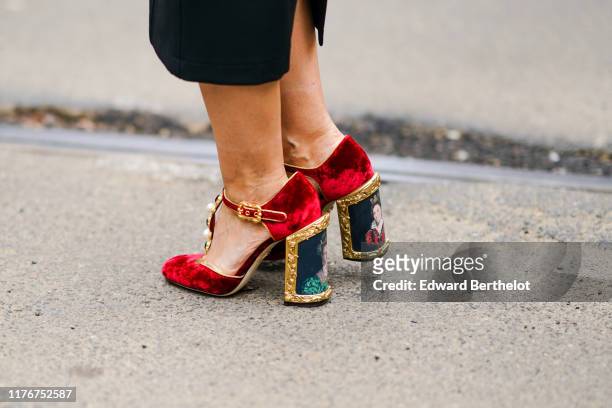 Guest wears bejeweled red velvet T-strap shoes with queens' portraits print on the heels, outside the Dolce & Gabbana show during Milan Fashion Week...