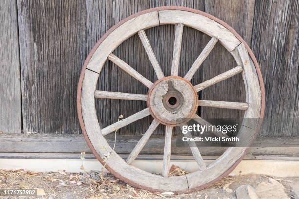 old wooden wagon wheel against a wooden shed - carriage wheel stock pictures, royalty-free photos & images