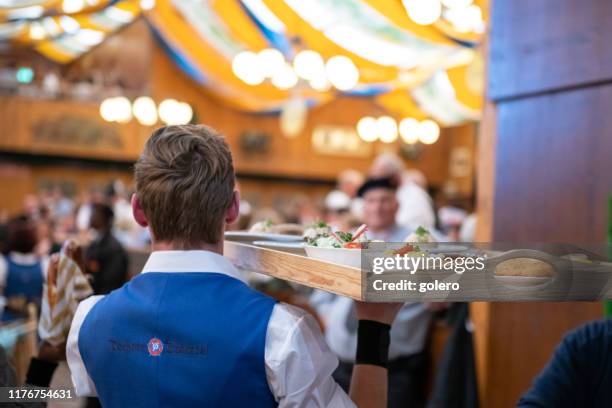 kellner mit futter für den oktoberfest-gast - gastronomiebetrieb stock-fotos und bilder