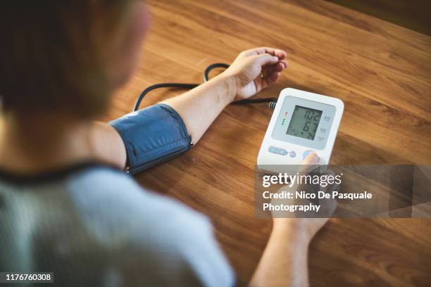 woman checking blood pressure - blood pressure stock-fotos und bilder