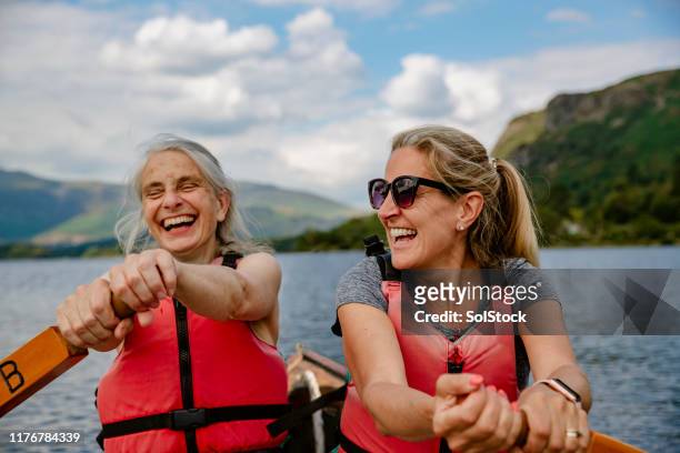 señoras maduras divirtiéndose en un bote de remo - mujer 50 años fotografías e imágenes de stock