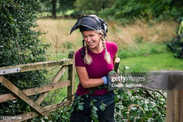 female tree surgeon pulling tree branch through gate - landscape architect stock pictures, royalty-free photos & images