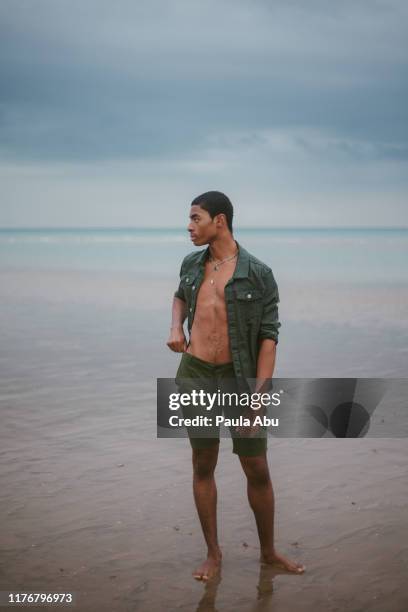 young man on beach - grünes hemd stock-fotos und bilder