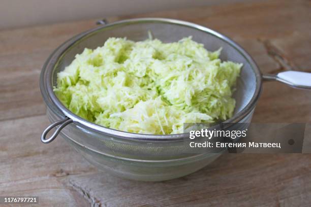 grated zucchini in a glass bowl and wooden board. cooking vegetable harvesting concept - grated zucchini stock pictures, royalty-free photos & images