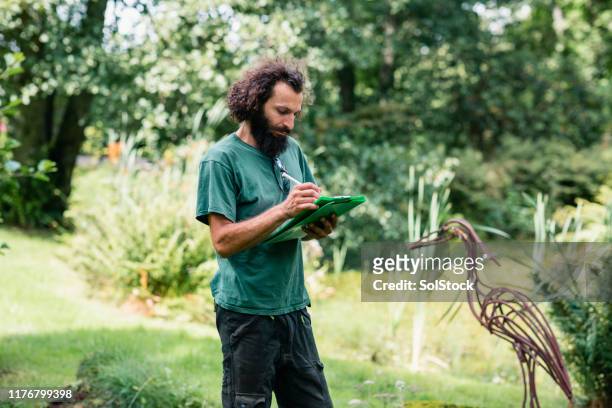 landscape gardener making notes on clipboard in garden - landscape architect stock pictures, royalty-free photos & images