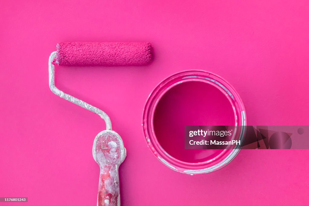 Roller and paint can on fuchsia colored surface
