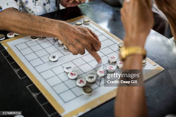 men play a board game outside the buddha tooth relic temple in the chinatown district of singapore. - singaporean culture stock pictures, royalty-free photos & images