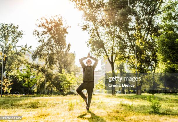 senior man doet yoga buitenshuis in city park. - man doing yoga in the morning stockfoto's en -beelden