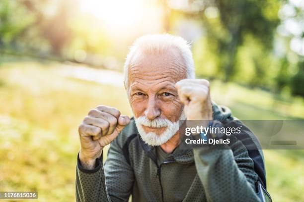sportlicher senior mann liebt boxen und ist stärker als je zuvor. - kampfpose stock-fotos und bilder