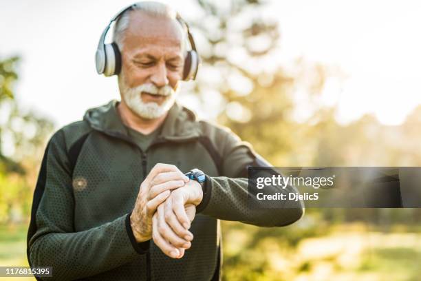 senior man using digital watch outdoors. - active seniors winter stock pictures, royalty-free photos & images