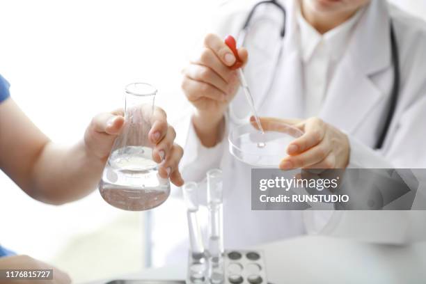 doctor putting liquid in petri dish - ビーカー ストックフォトと画像