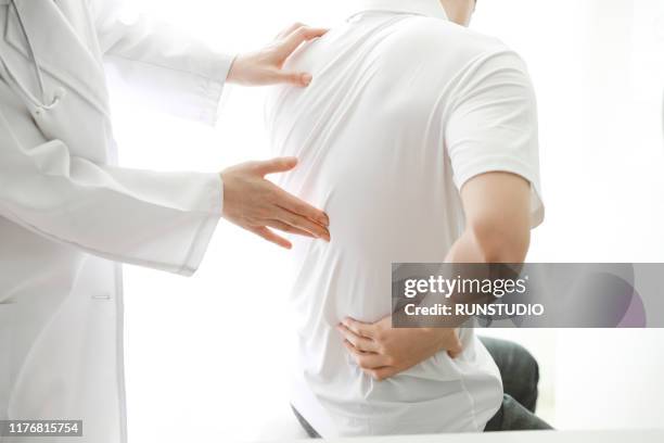 doctor checking patient's backache - dolor de espalda fotografías e imágenes de stock