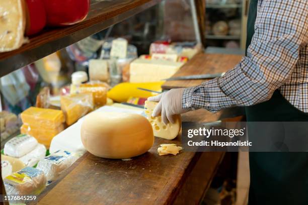 unkenntlich mann schneiden käse in einem feinkostladen - käselaib stock-fotos und bilder