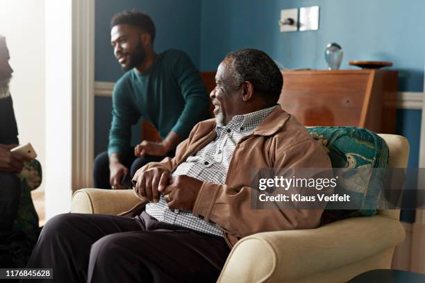 senior man looking at male friends talking at home - male at home imagens e fotografias de stock