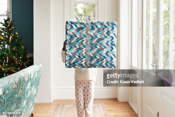 girl carrying large christmas present at home - carrying gifts stock pictures, royalty-free photos & images