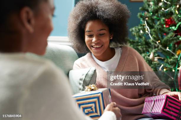 girl giving christmas present to sister at home - 14 year old biracial girl curly hair stock pictures, royalty-free photos & images