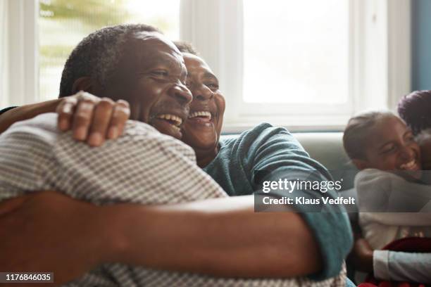romantic senior couple embracing on sofa at home - flouté photos et images de collection