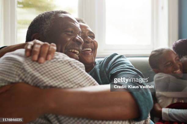 Romantic senior couple embracing on sofa at home