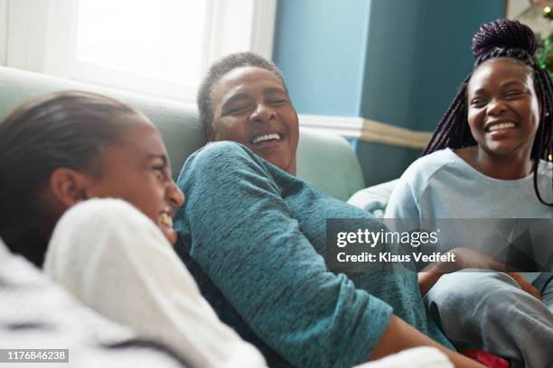 grandmother relaxing with granddaughters on sofa - black grandma stockfoto's en -beelden