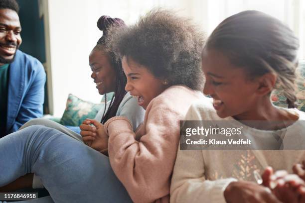 man looking at playful sisters sitting at home - 14 year old biracial girl curly hair stock pictures, royalty-free photos & images