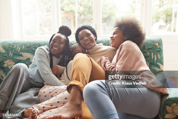 portrait of happy woman embracing girls at home - teen sibling stock pictures, royalty-free photos & images