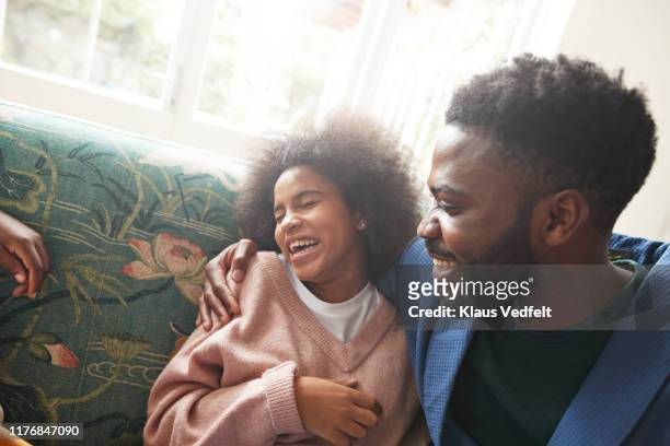 young man embracing cheerful teenage girl on sofa - sister stock photos et images de collection