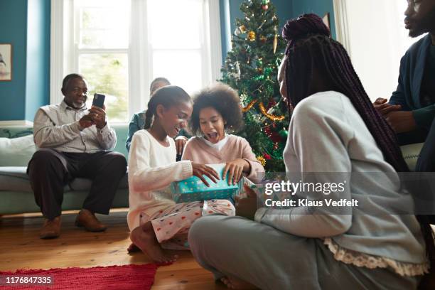 excited sisters opening christmas presents at home - child giving gift ストックフォトと画像