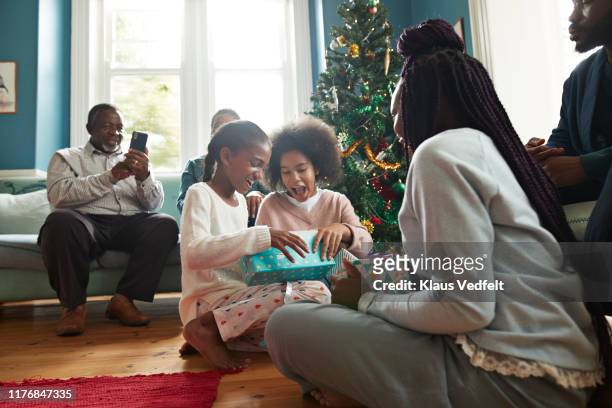 excited sisters opening christmas presents at home - multi generation family christmas stock pictures, royalty-free photos & images