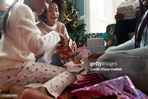 happy sisters opening christmas presents at home - geschenke weihnachten stock-fotos und bilder
